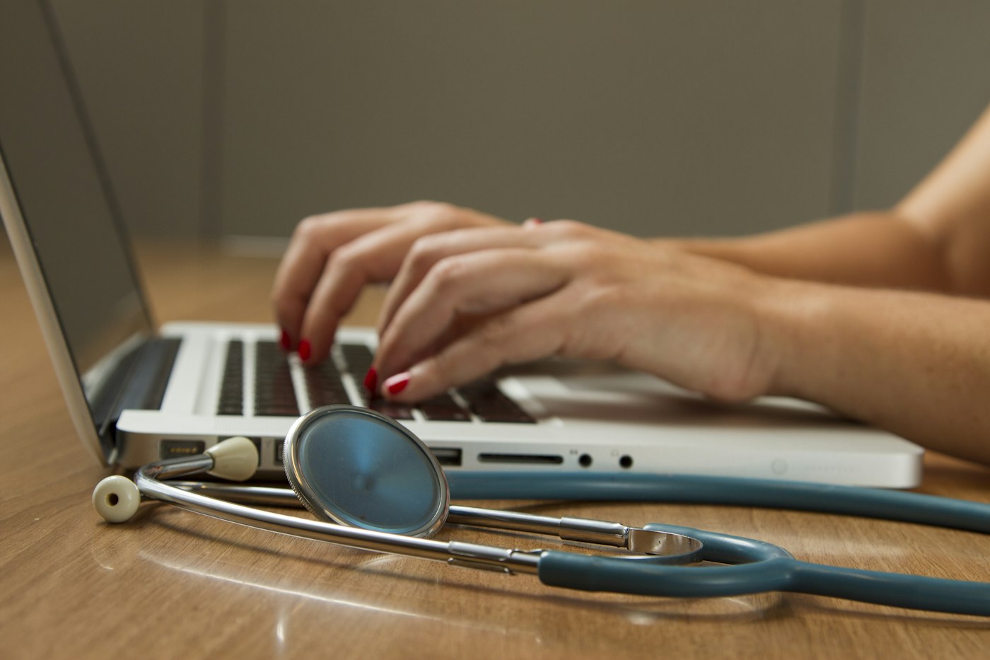 Stethoscope beside a laptop on a wooden desk